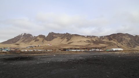 icelandic landscape with houses with black volcanic beach