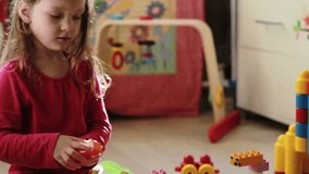 Cute little girl playing with toy blocks at home in the morning