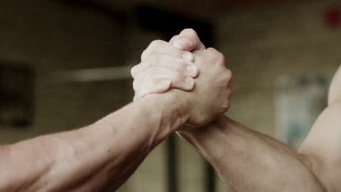 Closeup shot of two strong men having firm handshake after training in gym
