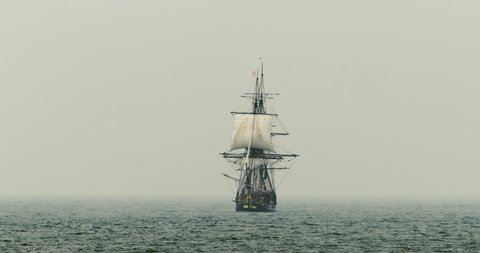 A tall ship schooner sails on the high seas in misty fog.