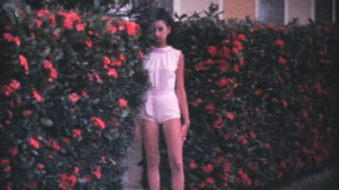 PENSACOLA, FLORIDA, JUNE 1969: An attractive young college aged girl poses in front of a hedge while on holidays in the summer of 1969 in Florida.