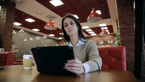 Young happy woman using tablet computer touchscreen in cafe 