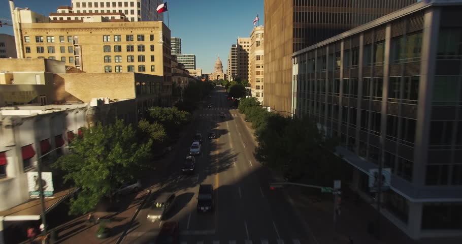 The camera flies north over Congress Avenue in Austin, Texas as it gains altitude to showcase the state capitol building. 