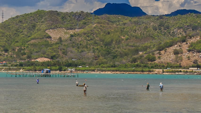 Vietnamese workers measure sea level with special instruments in azure bay of hilly green island