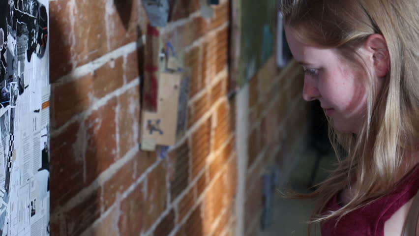 Handheld close up shot of a young woman looking at collage art.