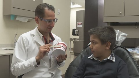 Dentist Shows Young Boy How To Brush Teeth- Medium Shot