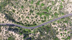 Coastal Aerial view of vehicle (car) traveling through windy sandhills on outback coastal road highway with sandy dunes each side. Nice sunny holiday travel, camping or lost in the wilderness theme.
