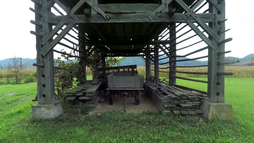 In this video, we can see a trailer located in the hayrack and there is also other equipment stored for harvest there too. Close-up shot.