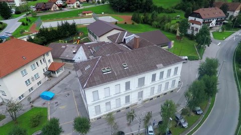 This video shows a big school located in the middle of a small town. The school outside is beautiful but its roof needs to be renovated.