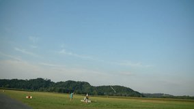In this video, we can see a young sky diver landing in the middle of nature and his parachute closes after him. Wide-angle shot. The day is sunny and beautiful.