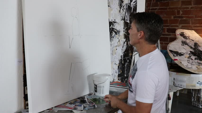 Medium shot of an artist drawing on a large canvas.