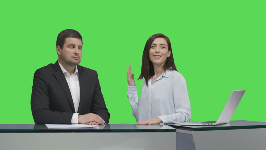 Male and female broadcasters are sitting at a table and talking on a mock-up green screen in the background. Shot on RED Cinema Camera in 4K (UHD).