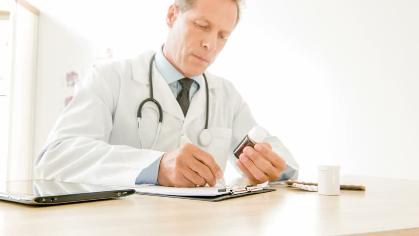 Copying drug info. Medic sitting at his desk and accurately writing down remedy instructions to use. | Shutterstock HD Video #12943493