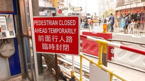 HONG KONG - FEBRUARY 09, 2015: Road reconstruction area, walk behind fence, watch red sign message. Day city life on back. Compact area full of alerts, fence parts, sign boards. Excavated road behind