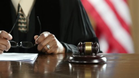 Judge's hand banging a gavel in a courtroom