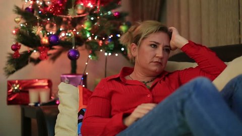 Depressive woman lying on a sofa in living room with christmas decorating