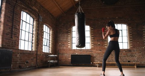 Beautiful Kickboxing woman training punching bag in fitness studio fierce strength fit body slow motion