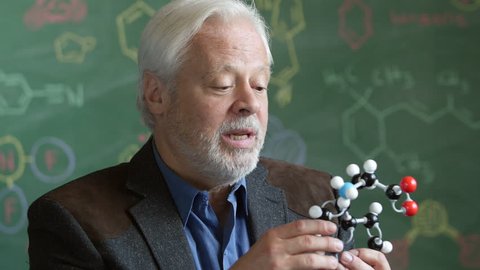 A Chemistry professor holding a molecular model in a classroom Video Stok