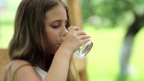 Beautiful girl drinks clean water from a glass