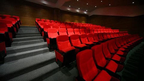 Panning of red arm-chairs and gangway are in empty hall 