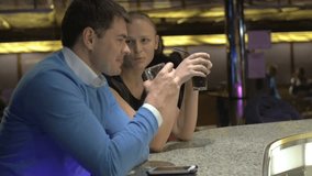 Slow motion clip of a happy caucasian couple with cocktails sitting at the bar