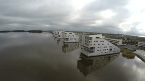 Aerial view from sky drone clip of white grey sea view apartment buildings flying backwards away showing modern architecture and city overcast weather quiet water coastline white buildings 4k