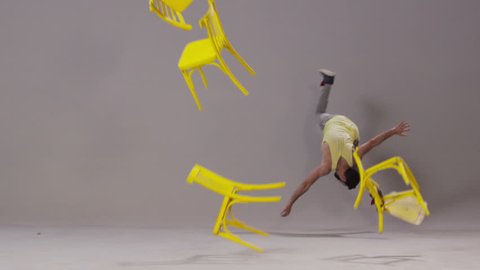 Boy flips, jumping, dancing. Falls yellow chairs. Slow Motion. 