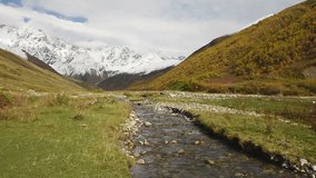 Amazing touristic place near river in mountain valley at the foot of Mt. Shkhara 5,193 m (17,040 ft). Upper Svaneti, Georgia, Europe. Caucasus mountains. HD video clip (High Definition)

