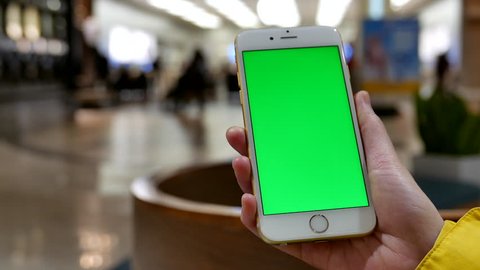 Coquitlam, BC, Canada - November 25, 2015 : 4k of woman holds a blank smart device with a green screen for your own custom content in front of apple store