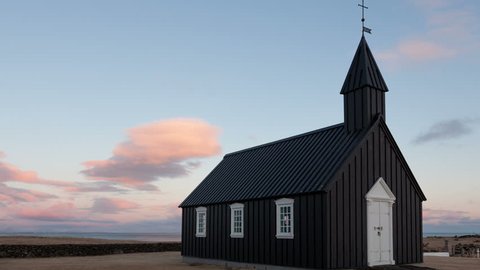 4K Timelapse of the black wooden church in Budir, Iceland at sunset in wide angle view with clouds passing by