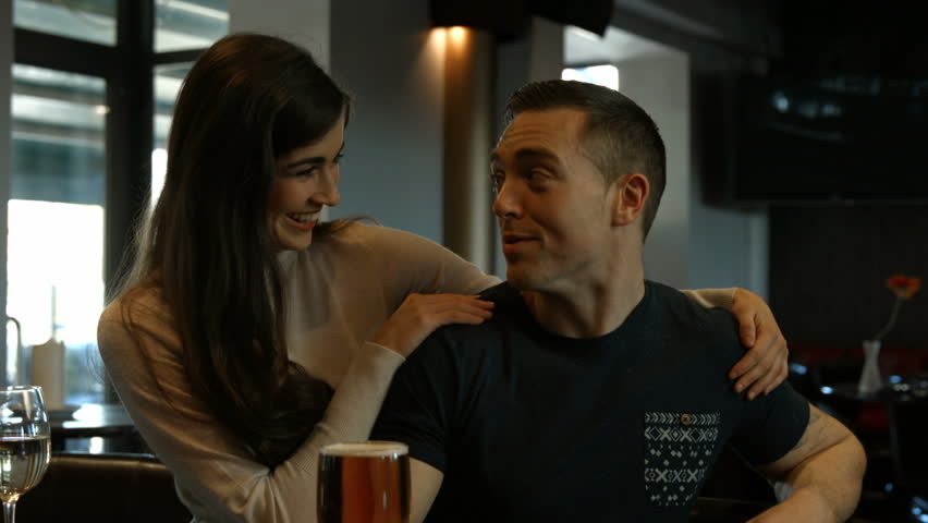 Smiling couple talking at counter in bar