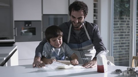 Father and son baking biscuits in Kitchen