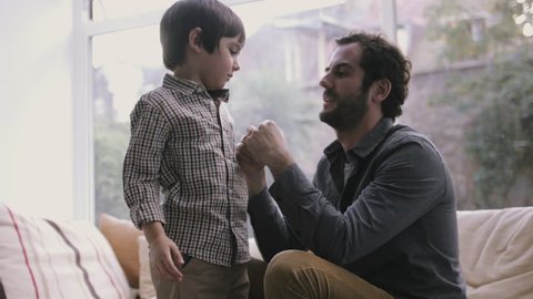 Father buttoning little son's shirt
