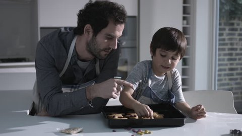 Father and son baking biscuits in Kitchen