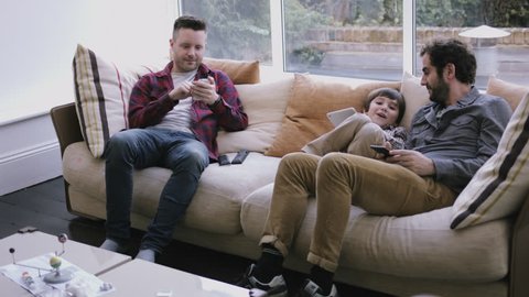 Same sex couple family on the couch working with digital tablet and smart phone