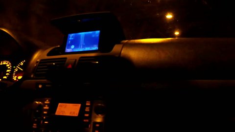 Cabin of a moving car at night. Steering wheel, speed meter and board lights.