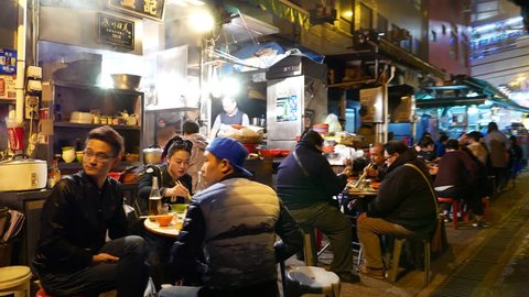 HONG KONG - FEBRUARY 10, 2015: Truly authentic chinese fast-food street in night, with sound. While all restaurants on first level of building closed in night time, many food-kitchen booth