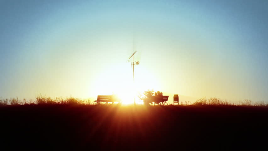 People silhouettes in parc, sitting on bench at sunset