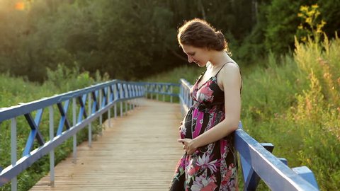 Happy pregnant woman caressing belly 