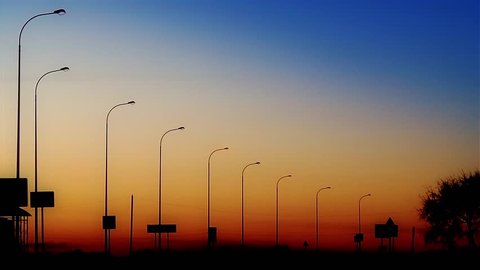 Street lights along the road turning on against twilight background