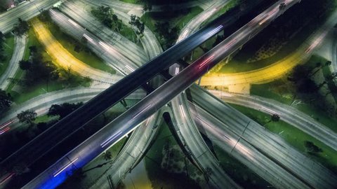 Vertical aerial view of traffic on freeway interchange at night. 4K UHD timelapse.