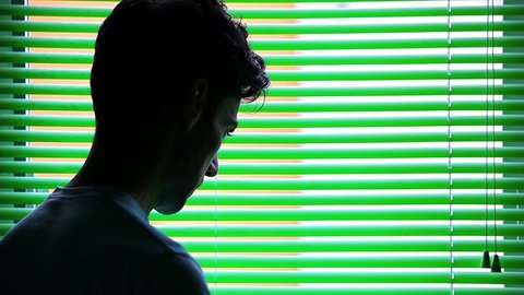 Sad young man worried in front of a venetian blind