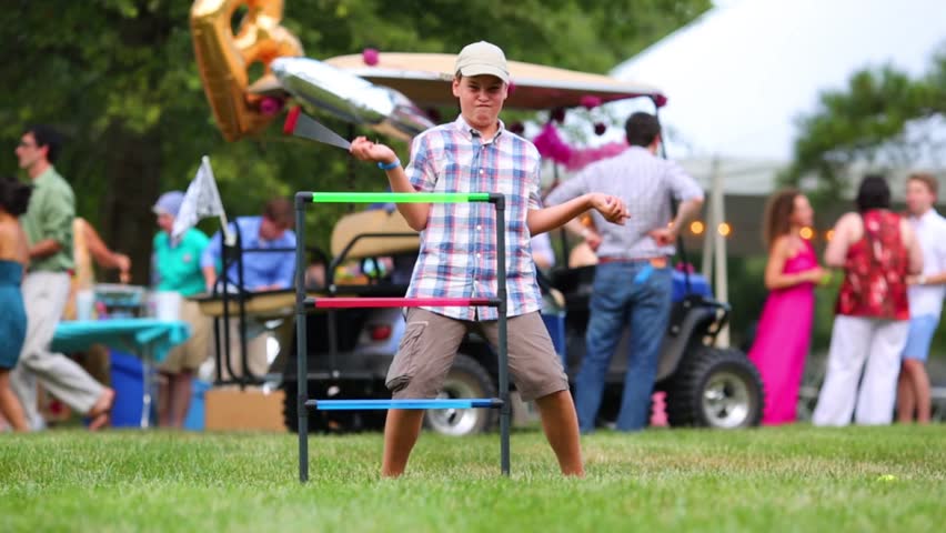 Happy boy plays lawnball in garden during holiday at evening