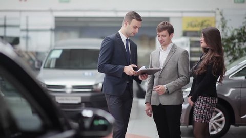Salesman transmitting keys to young couple in car dealership