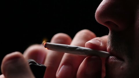 Man lighting a joint, close up on black