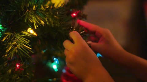 Child Putting Christmas Ornament on Pine Tree of Santa Claus