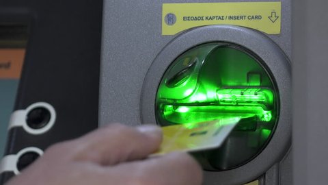 Atm machine inserting card on slot.The hand of a man pushing a debit card on the slot of the atm machine in Greece.