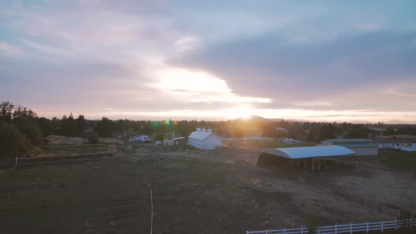 Sunset over western barn scene with mountains in the background
