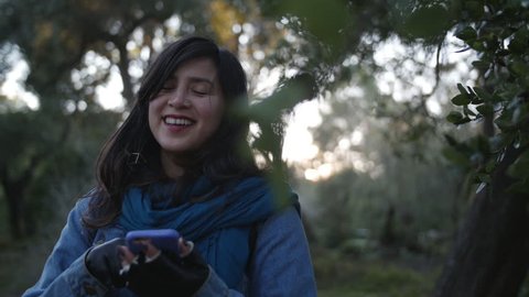 Young woman using phone in woods.