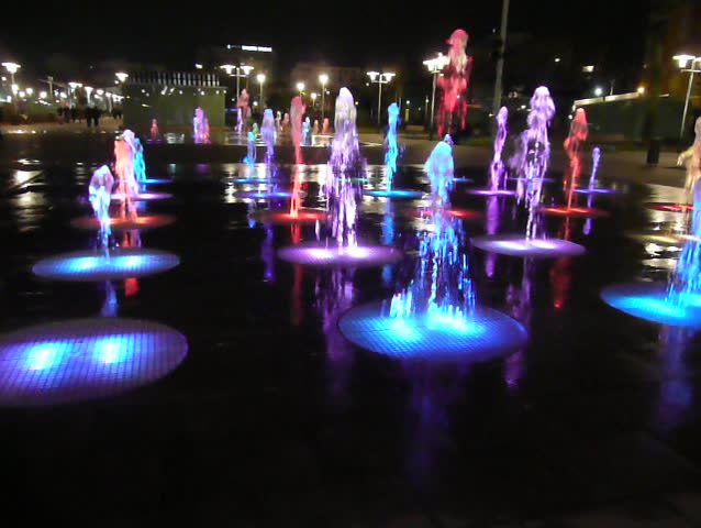 Water fountain lit by coloured lights at night